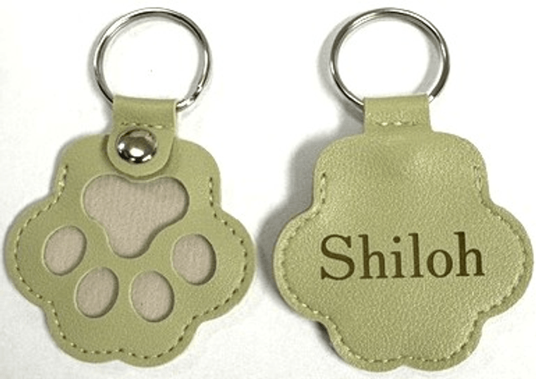 front and back of a sage leather paw key chain: paw print cutouts on the front, the name Shiloh engraved on the back