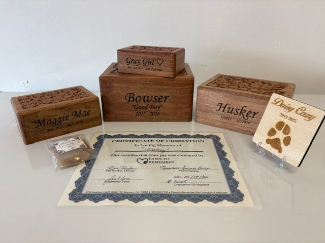 standard package contents: engraved wooden urns with carved lids, a wooden paw print keepsake, a certificate of cremation, and a bagged clipping of hair