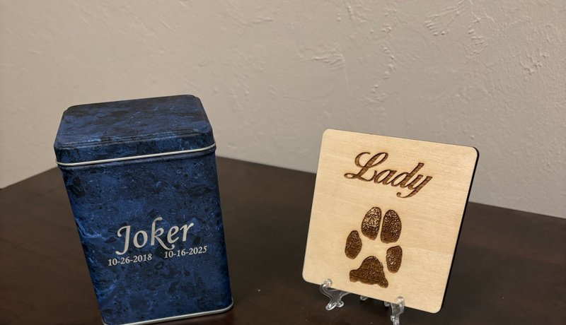 standard package contents: an engraved metal box for the cremains, a wooden paw print keepsake, a certificate, and a bagged clipping of hair